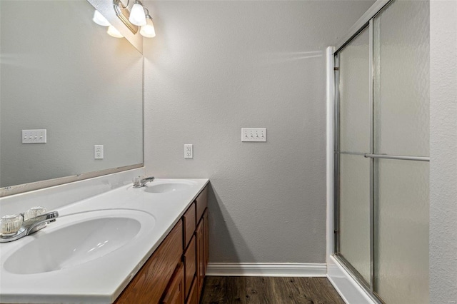 bathroom with hardwood / wood-style floors, vanity, and a shower with shower door