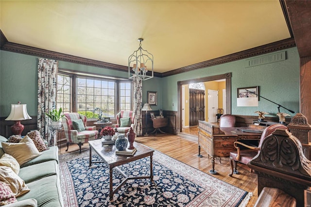 living room featuring a chandelier, crown molding, and light hardwood / wood-style floors