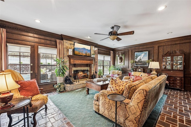 living room with wood walls, ceiling fan, and a healthy amount of sunlight