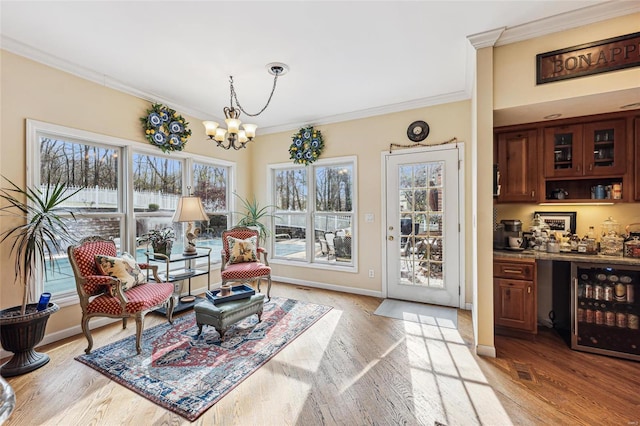 living area featuring wine cooler, light hardwood / wood-style floors, crown molding, and a wealth of natural light