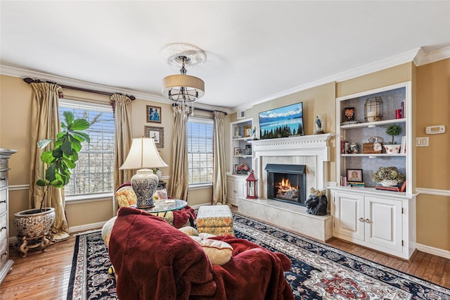 living room featuring light wood-type flooring, built in features, crown molding, and a premium fireplace