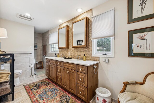 bathroom featuring plenty of natural light, vanity, tile walls, and toilet