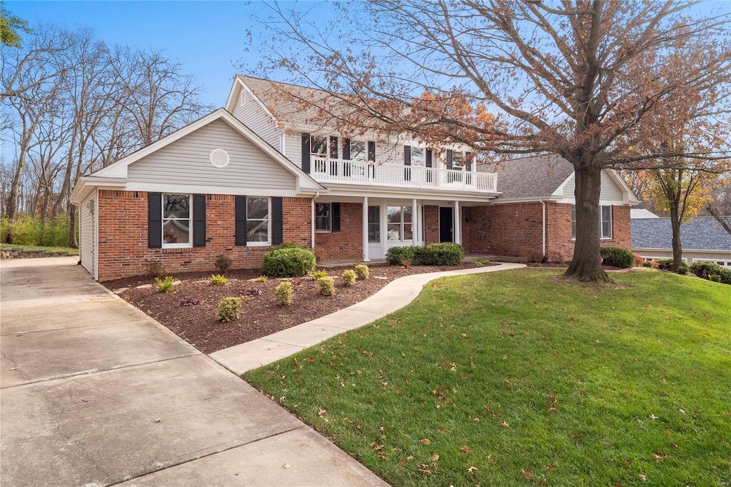 view of front of property featuring a front yard, a porch, and a balcony