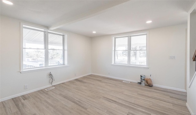 empty room featuring light wood-type flooring, visible vents, plenty of natural light, and baseboards