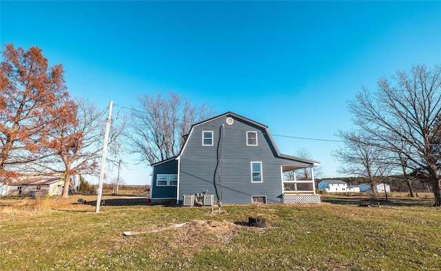 back of property featuring a gambrel roof, a lawn, and a sunroom