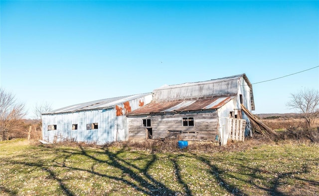 rear view of property with a barn, an outbuilding, and a lawn