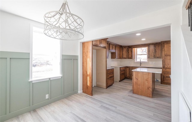 kitchen with a sink, recessed lighting, light wood-style floors, brown cabinetry, and light countertops