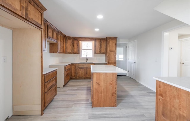 kitchen featuring a kitchen island, light wood-type flooring, recessed lighting, brown cabinetry, and a sink