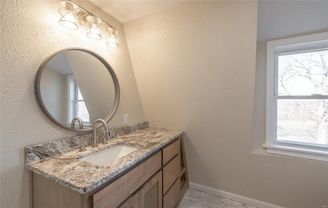 bathroom with marble finish floor, vanity, a healthy amount of sunlight, and baseboards