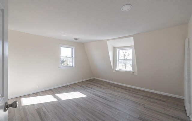 unfurnished room with a healthy amount of sunlight, baseboards, and wood finished floors