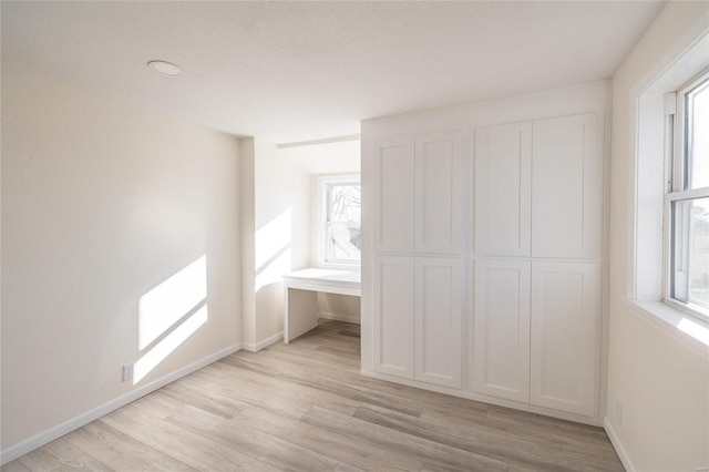 unfurnished bedroom with baseboards and light wood-type flooring