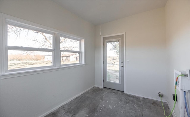 doorway to outside with baseboards and concrete flooring