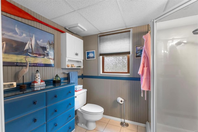 bathroom with tile patterned floors, a drop ceiling, toilet, and walk in shower