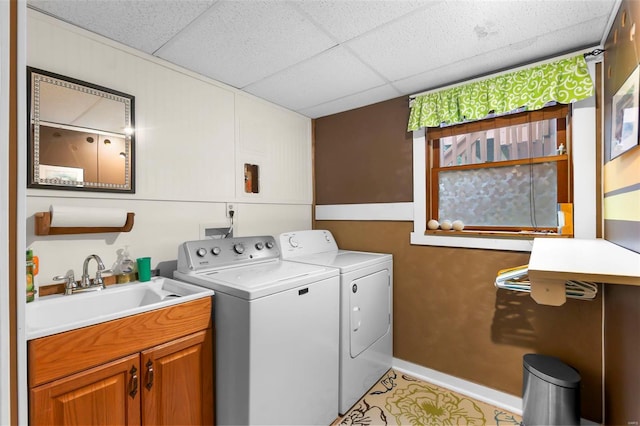 clothes washing area featuring washing machine and clothes dryer, sink, and cabinets