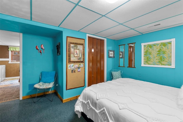 bedroom with a paneled ceiling and carpet floors