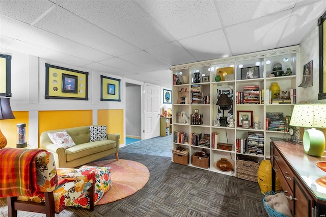 sitting room featuring a paneled ceiling and dark carpet