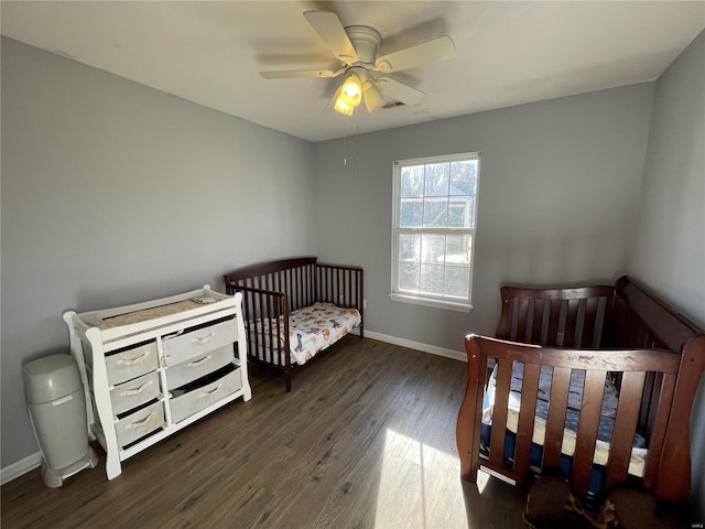 bedroom featuring ceiling fan, dark hardwood / wood-style flooring, and a nursery area