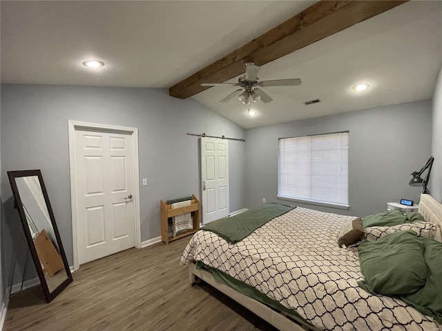 bedroom featuring a barn door, ceiling fan, wood-type flooring, and lofted ceiling with beams