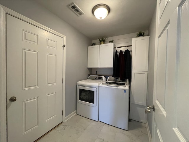 clothes washing area featuring cabinets and washing machine and dryer