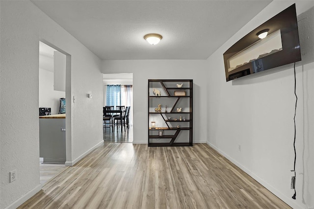 hall with a textured ceiling and light wood-type flooring