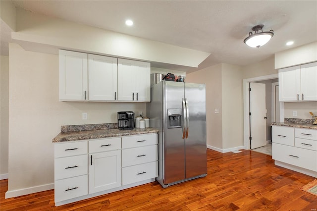 kitchen with white cabinets, stainless steel refrigerator with ice dispenser, and hardwood / wood-style floors