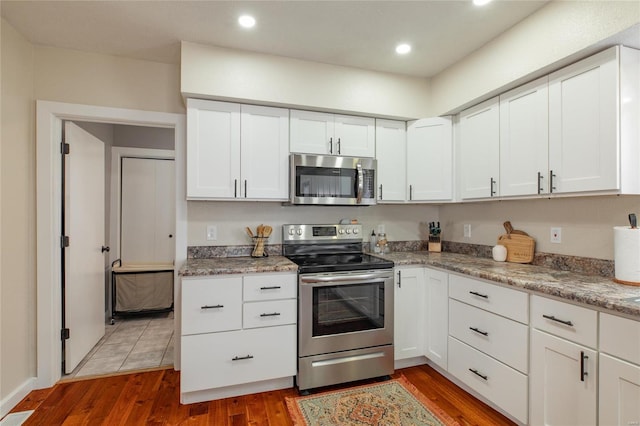 kitchen featuring dark hardwood / wood-style floors, white cabinetry, and stainless steel appliances