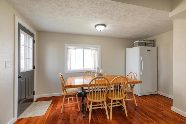 dining space featuring a textured ceiling, a wealth of natural light, and dark wood-type flooring