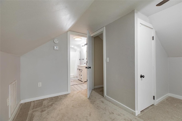 bonus room featuring a textured ceiling, lofted ceiling, and light carpet