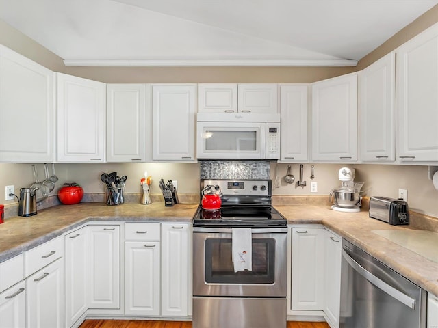 kitchen featuring white cabinets, stainless steel appliances, and vaulted ceiling