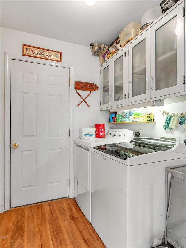 laundry area featuring cabinets, light wood-type flooring, and separate washer and dryer