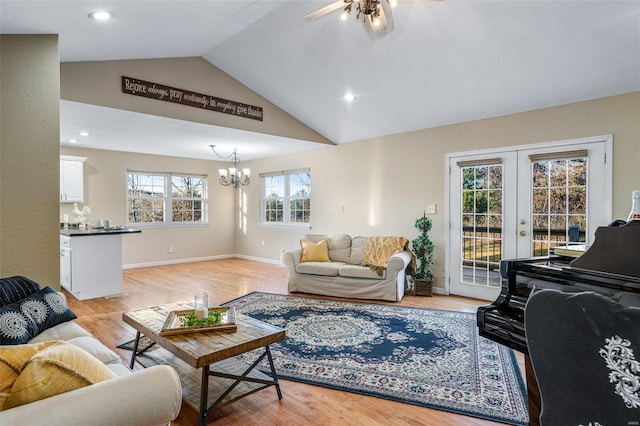 living room featuring a notable chandelier, french doors, lofted ceiling, and light wood-type flooring