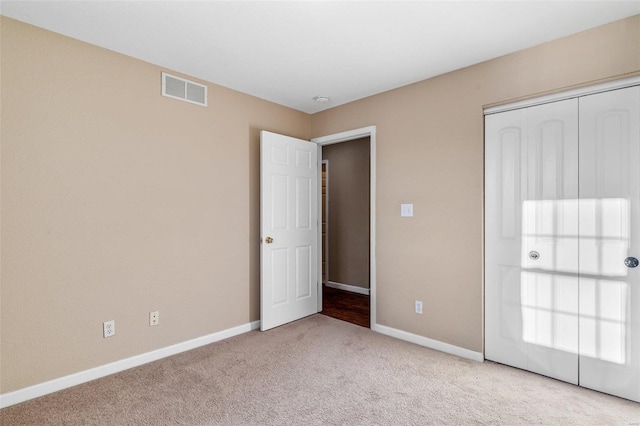 unfurnished bedroom with light colored carpet and a closet