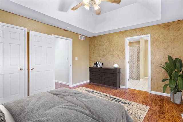 bedroom with ensuite bath, ceiling fan, and hardwood / wood-style floors