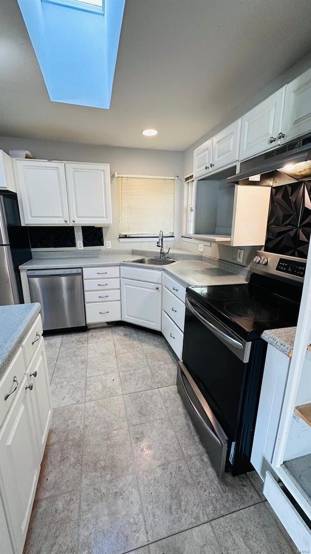 kitchen with white cabinets, stainless steel appliances, a skylight, and sink