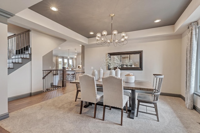 carpeted dining space featuring a chandelier and a tray ceiling