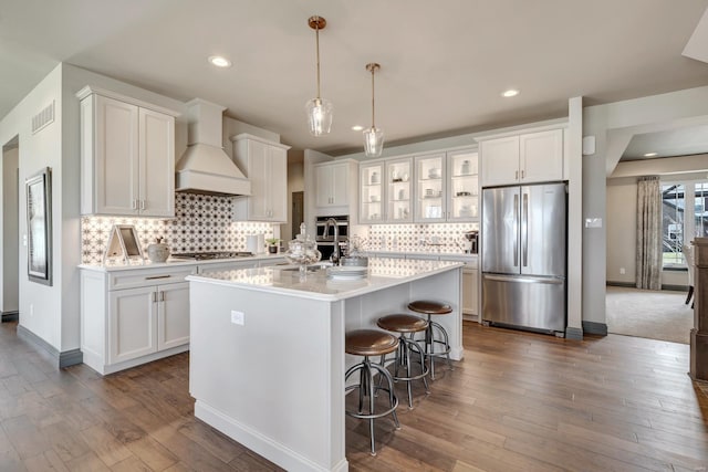 kitchen featuring white cabinetry, custom range hood, and appliances with stainless steel finishes