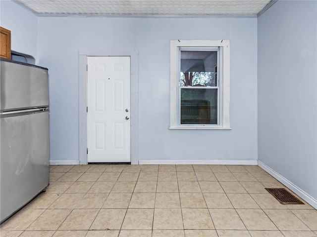 interior space with stainless steel fridge, a textured ceiling, light tile patterned floors, and crown molding