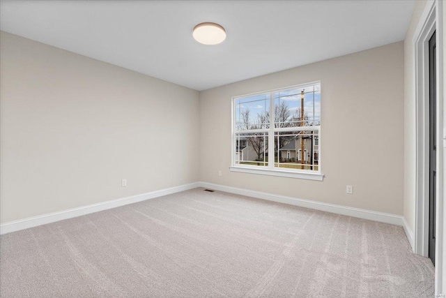 spare room featuring carpet flooring, visible vents, and baseboards