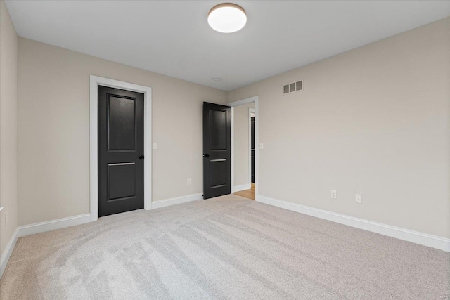 unfurnished bedroom with visible vents, light carpet, and baseboards