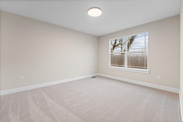 spare room featuring light carpet and baseboards