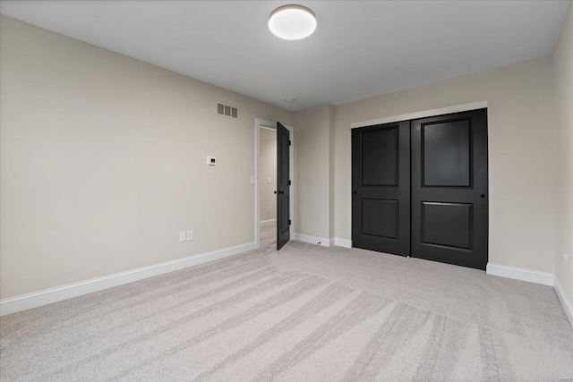 unfurnished bedroom with light carpet, a closet, visible vents, and baseboards