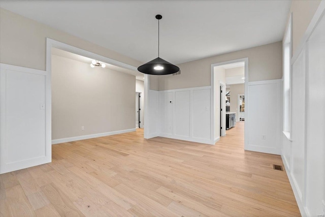 unfurnished dining area featuring light wood finished floors, baseboards, and visible vents