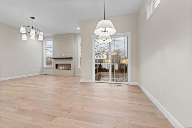 unfurnished living room with a large fireplace, light wood-style flooring, baseboards, and recessed lighting