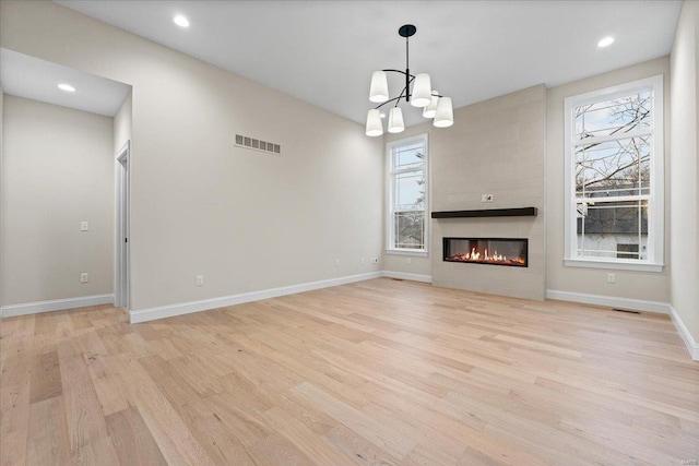 unfurnished living room with baseboards, a fireplace, visible vents, and light wood-style floors