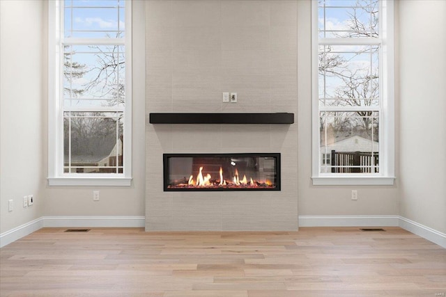 interior details with baseboards, a fireplace, visible vents, and wood finished floors