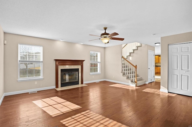 unfurnished living room featuring ceiling fan, wood-type flooring, a high end fireplace, and a textured ceiling