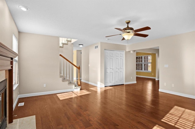 unfurnished living room with dark wood-type flooring, a high end fireplace, and ceiling fan