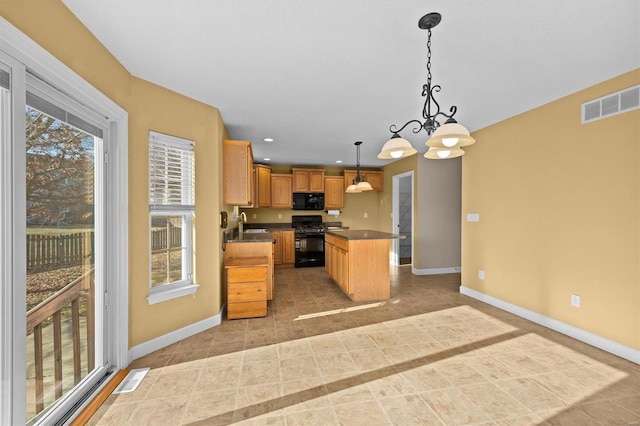 kitchen featuring pendant lighting, black appliances, a center island, and a healthy amount of sunlight