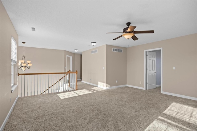 empty room featuring light carpet, ceiling fan with notable chandelier, and a textured ceiling