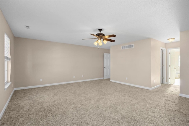 carpeted spare room featuring a textured ceiling, a wealth of natural light, and ceiling fan